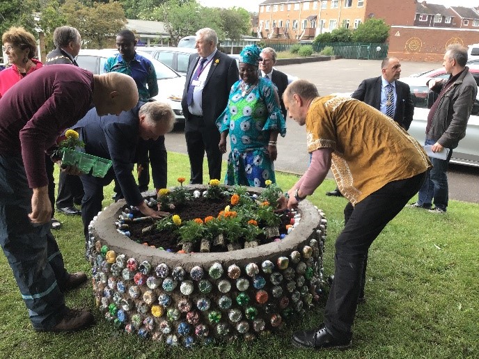 Bishop John of Warwick planting a marigold at The Day of the African Child, while other VIPs chat to OWL members.
